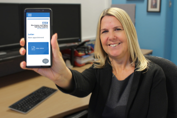 Staff member holding mobile phone with the digital patient portal on the screen.