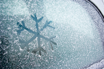 Image of car window with snow on it and a snow flake drawn on the window. 