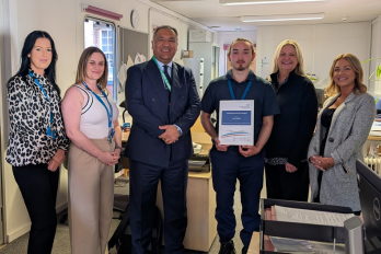 Image of supporting internship student holding the Chief Executive Award up with the Chief Executive and work colleagues.